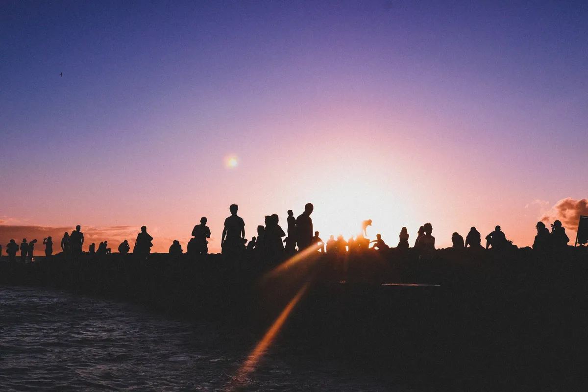 Menschen stehen bei Sonnenuntergang auf Hügel – Symbol für nachhaltige Zukunft und saubere Energie