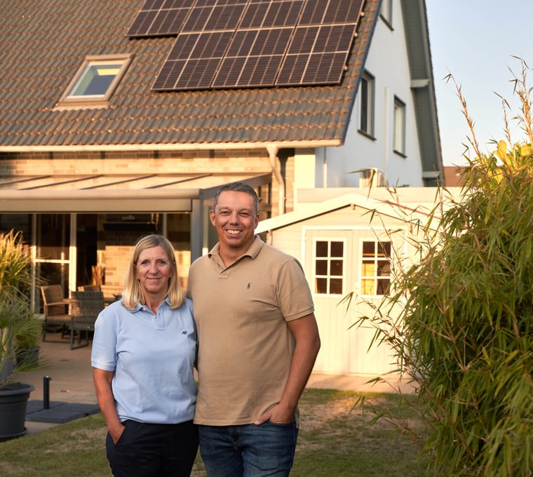Paar vor Einfamilienhaus mit Photovoltaikanlage auf dem Dach – eigener Solarstrom für ein nachhaltiges Zuhause