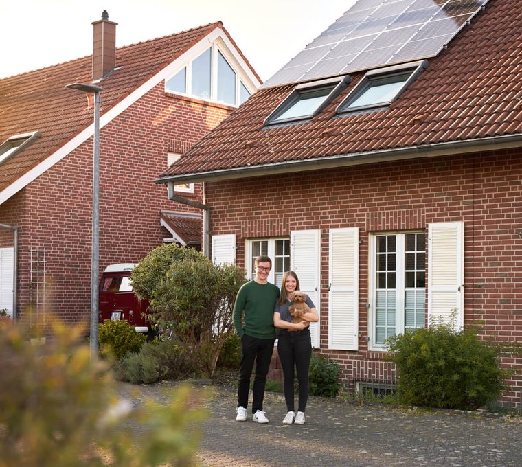 Hausbesitzer vor Reihenhaus mit Photovoltaikanlage auf dem Dach – Solarstromlösung für ein energieeffizientes Zuhause